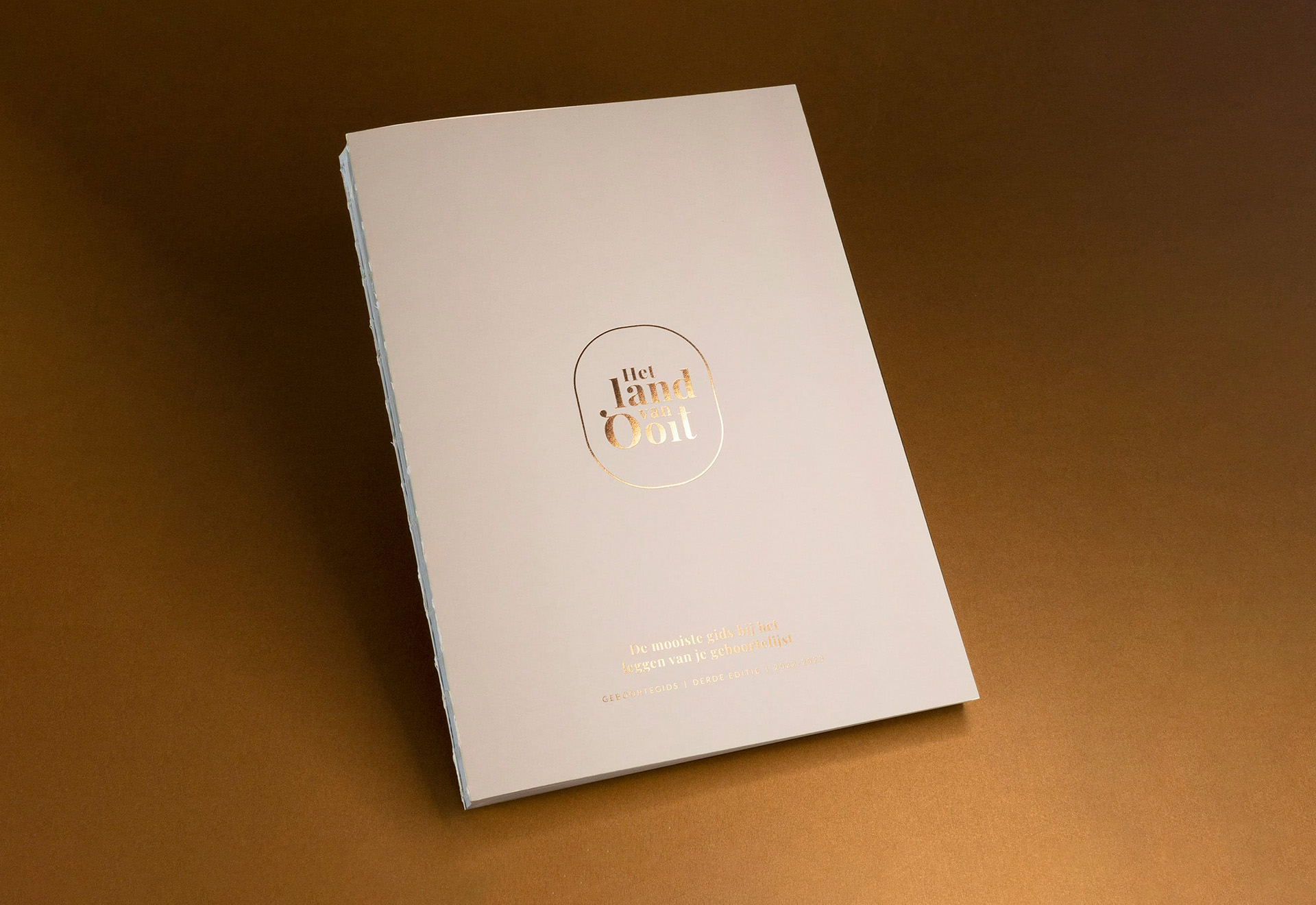 softcover catalogus met open rug en wit garen, cover voorzien van goudfolie op ongestreken papier